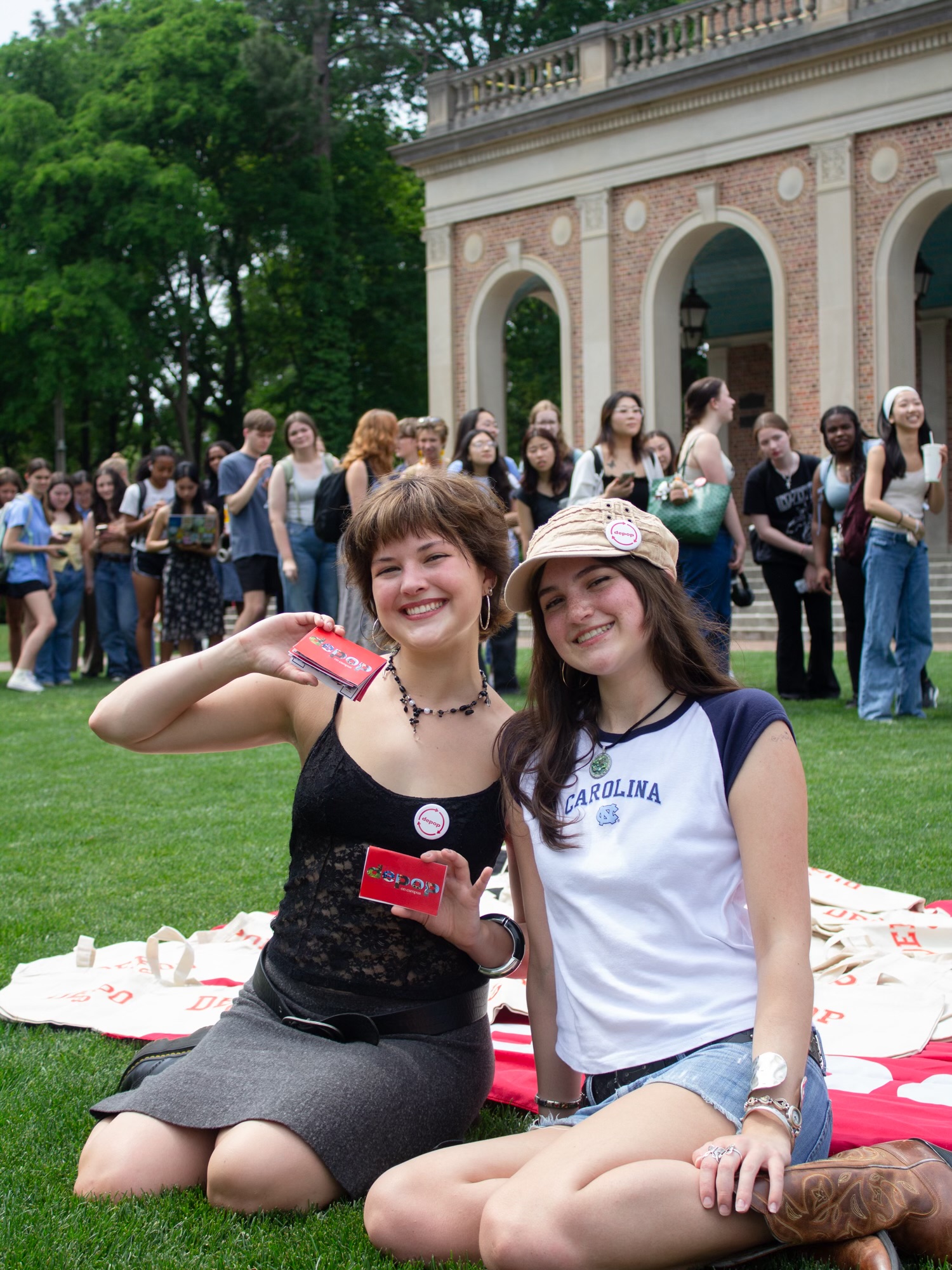 Photo of Ava and Savannah at their swap shop event at the UNC bell tower, holding zines